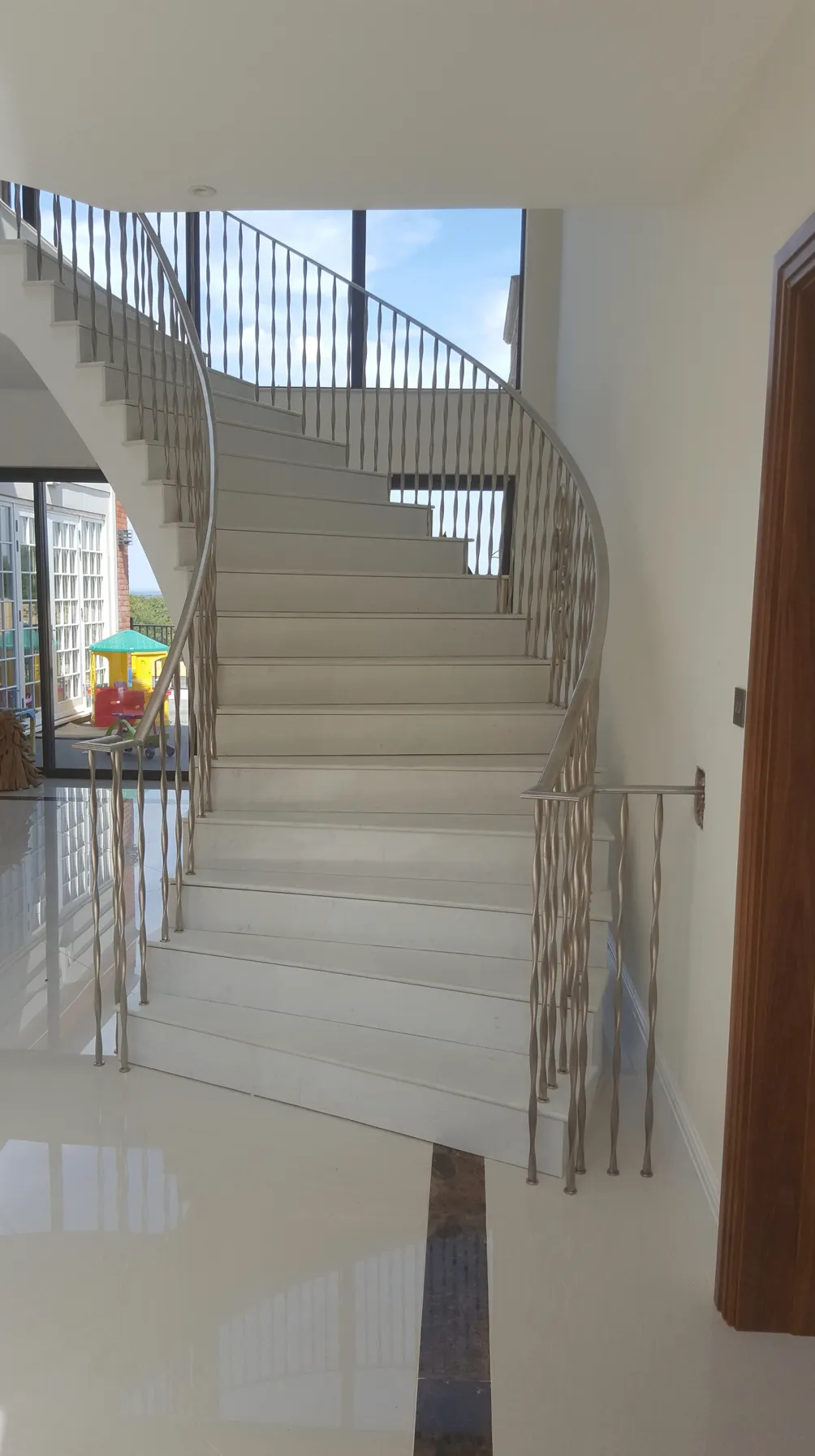 residential staircase made with stainless steel twisted oval tube spindles and d-shaped tube bannister