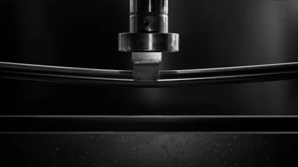 tubo arrotondato in acciaio inox lucidato a specchio sottoposto a stress test sotto un braccio idraulico