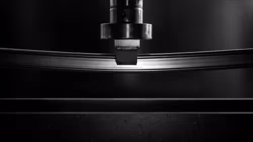 tubo a D in acciaio inox lucidato a specchio sottoposto a stress test sotto un braccio idraulico
