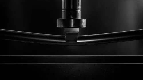 tubo ovale in acciaio inox lucidato a specchio sottoposto a stress test sotto un braccio idraulico