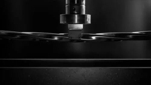 tubo quadro ritorto in acciaio inox lucidato a specchio sottoposto a stress test sotto un braccio idraulico
